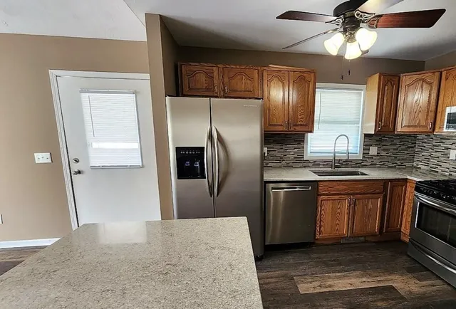 a kitchen with stainless steel appliances granite countertop a refrigerator a sink a stove and oven