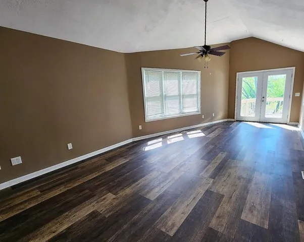 a view of an empty room with wooden floor fireplace and a window
