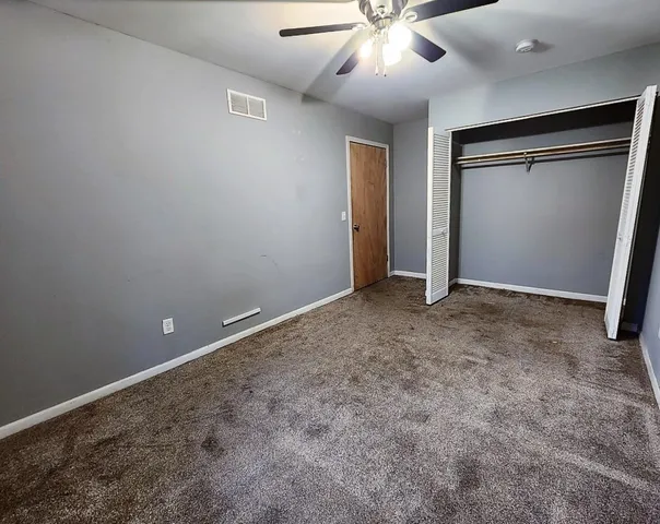 an empty room with closet and fan