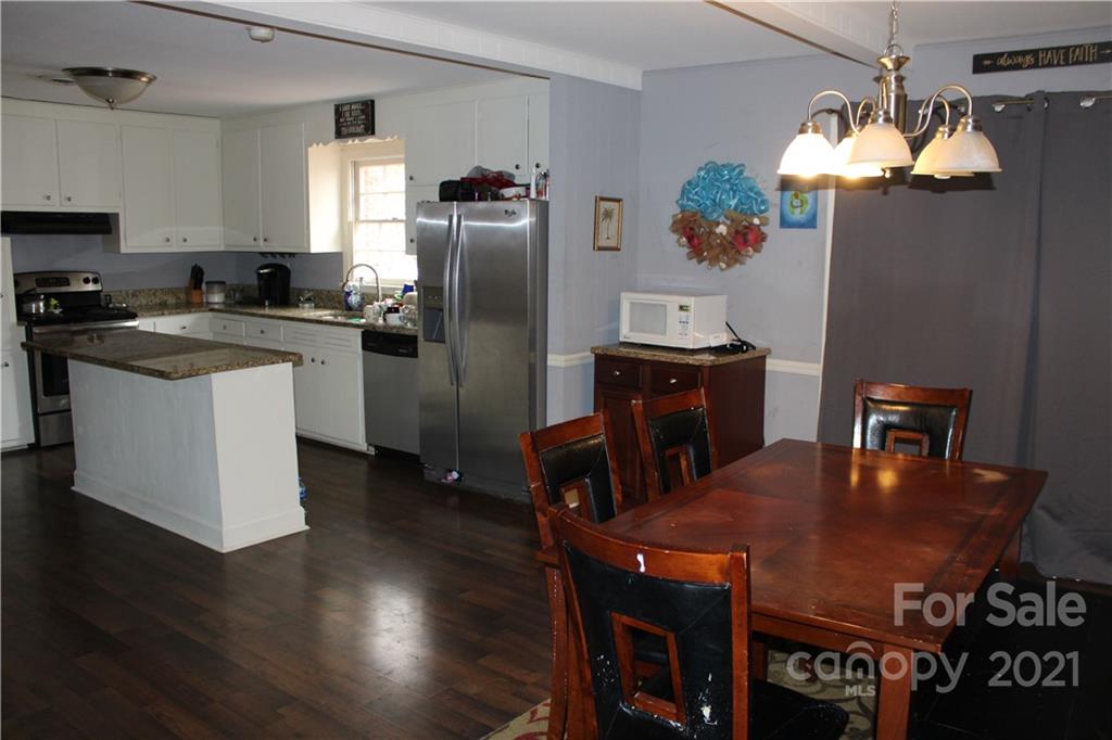 1021 Faith Road Salisbury, NC 28146 - Photo 5 of 12 a kitchen with stainless steel appliances granite countertop a dining table chairs refrigerator and a refrigerator