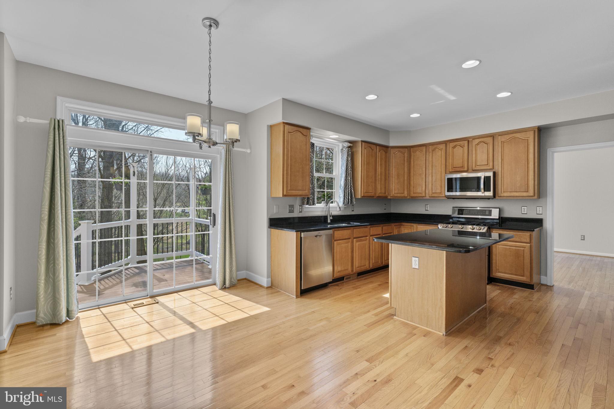 4520 Tulip Way Ellicott City, MD 21043 - Photo 2 of 63 a kitchen with granite countertop a stove a sink a refrigerator and white cabinets with wooden floor