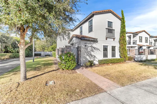 a view of a white house with large windows and a small yard
