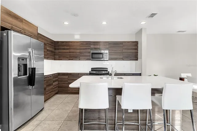 a kitchen with a stove a refrigerator and chairs