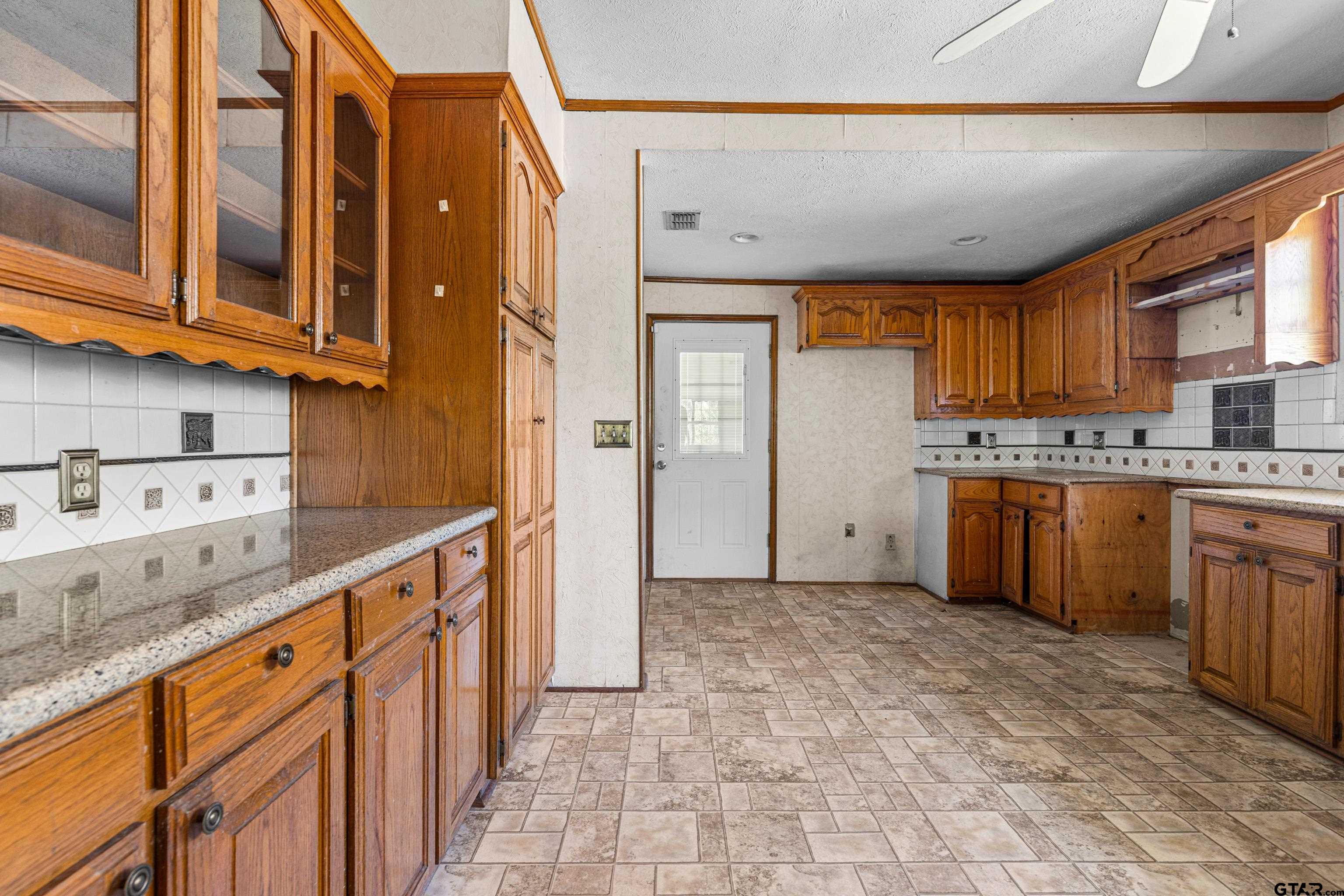 1159 County Road Mount Enterprise, TX 75681 - Photo 9 of 27 a kitchen with stainless steel appliances granite countertop a refrigerator a sink dishwasher and wooden cabinets with wooden floor