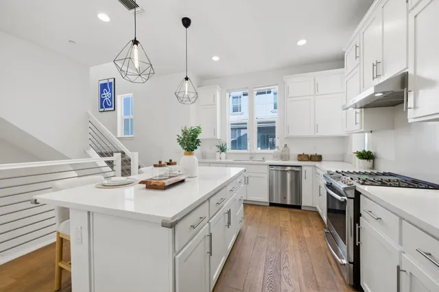 a kitchen with stainless steel appliances granite countertop a sink a stove a dining table and chairs