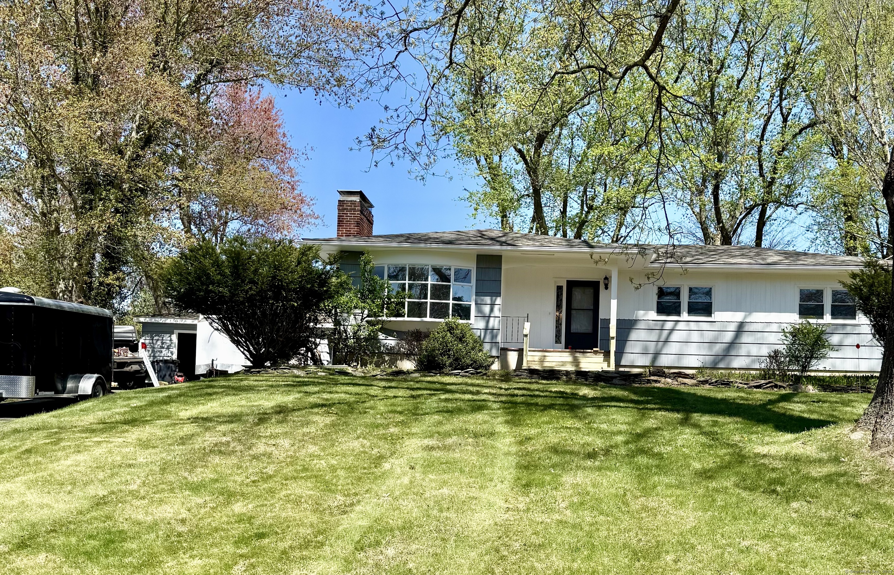 a front view of house with yard and trees in the background