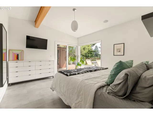 a bedroom with a bed and a flat tv screen on dresser