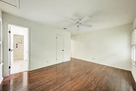 an empty room with wooden floor and ceiling fan