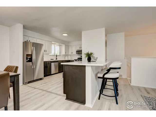 a kitchen with stainless steel appliances kitchen island granite countertop a refrigerator and a sink