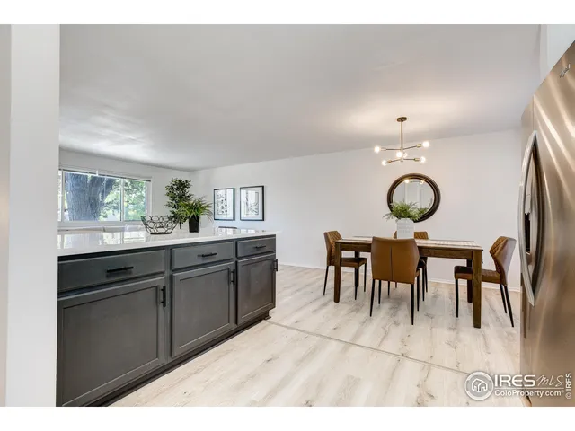a open kitchen with stainless steel appliances kitchen island granite countertop a table chairs and a refrigerator