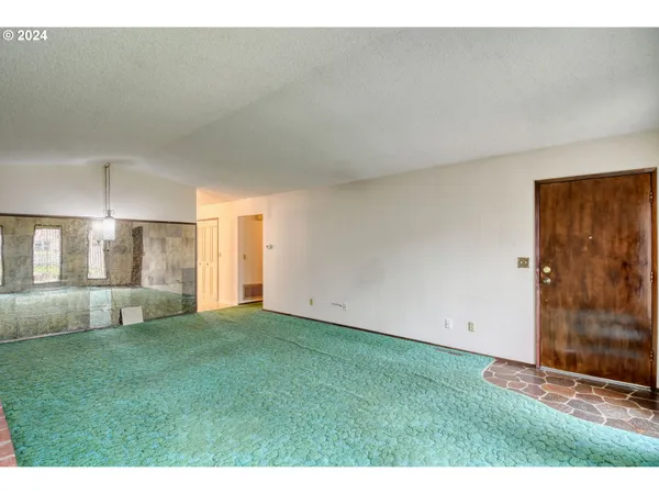 a view of an empty room with kitchen and a window