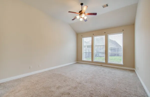 an empty room with chandelier fan and windows