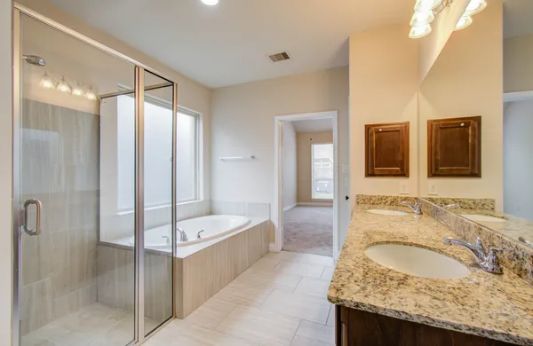 a bathroom with a granite countertop tub sink and mirror