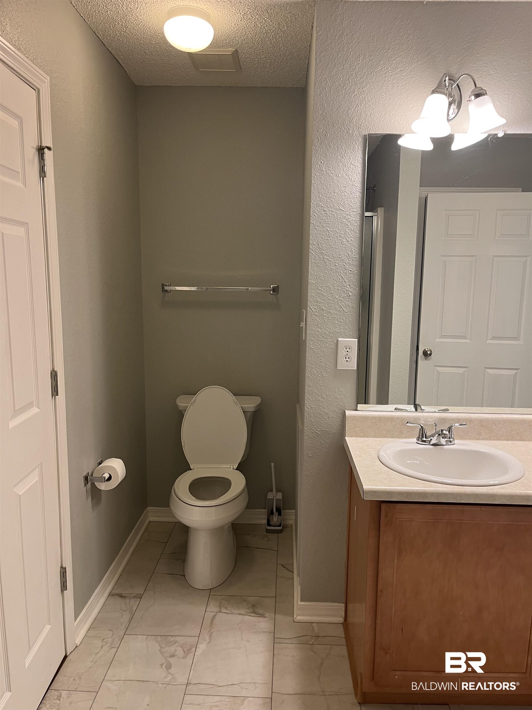 309 Cluster Street Foley, AL 36535 - Photo 17 of 38 Bathroom featuring a single vanity with wood-finish cabinetry, a neutral countertop, and a built-in sink