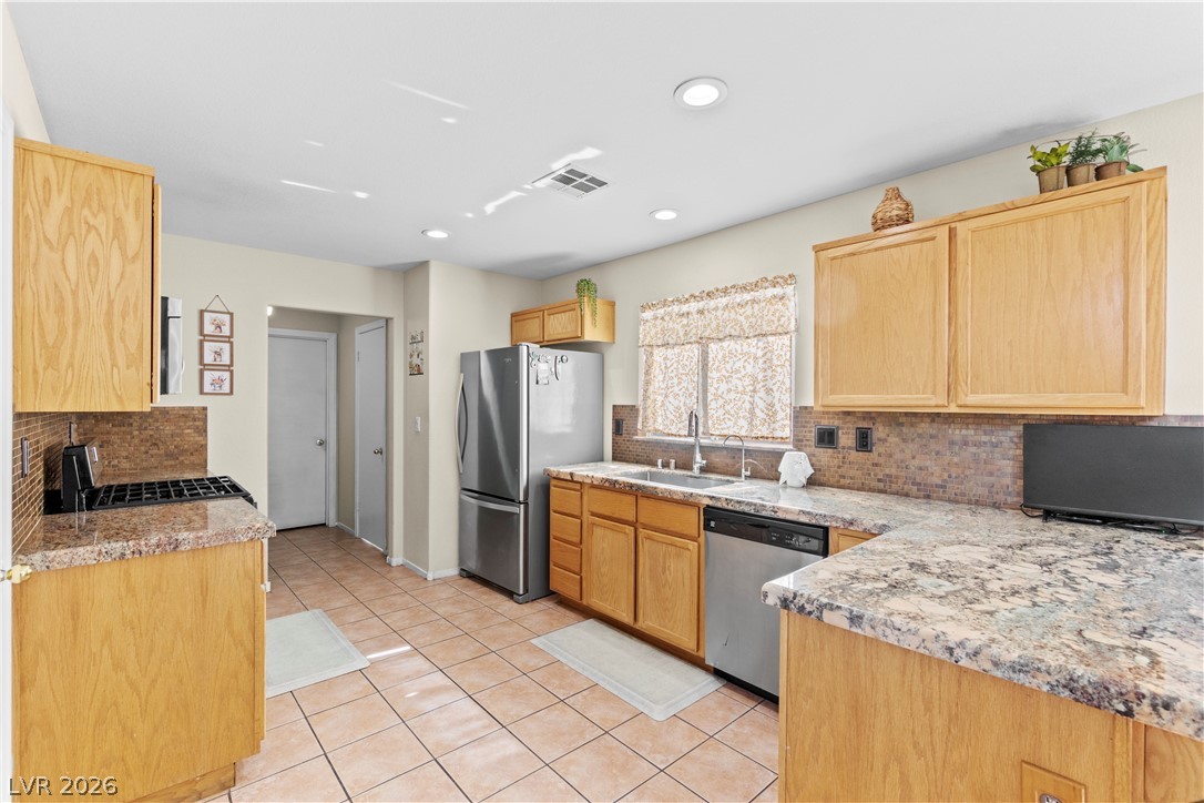1419 Red Sunset Avenue Henderson, NV 89074 - Photo 13 of 35 Kitchen with backsplash, light tile patterned flooring, stainless steel appliances, recessed lighting, and light stone counters