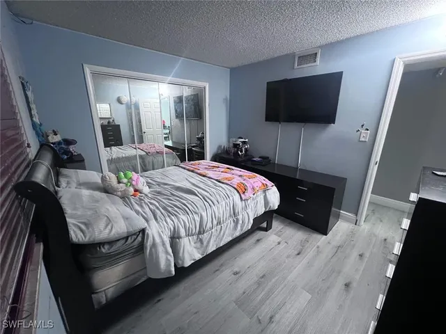 a bedroom with a bed and a flat tv screen on dresser