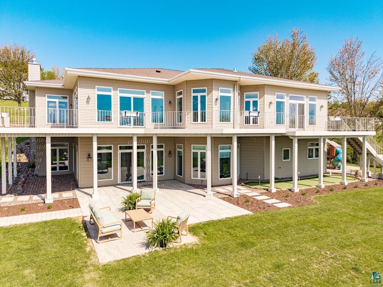 2906 West 15th Street Duluth, MN 55811 - Photo 6 of 98 Contemporary two-story exterior featuring extensive upper-level balconies with metal railings, a spacious lower-level patio, multiple large windows, and an artificial turf putting green
