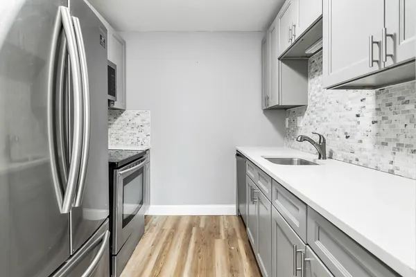 a kitchen with stainless steel appliances a sink a stove a refrigerator and cabinets