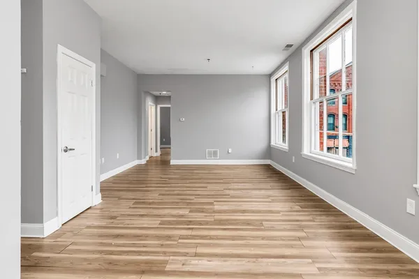 a view of empty room with wooden floor and fan