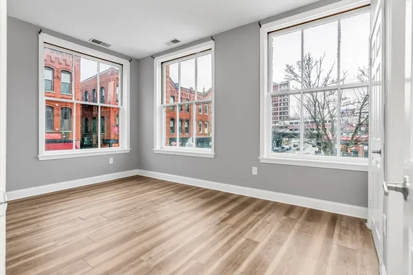 a view of an empty room with wooden floor and a window