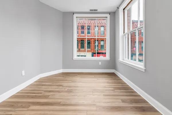 a view of an empty room with wooden floor and windows