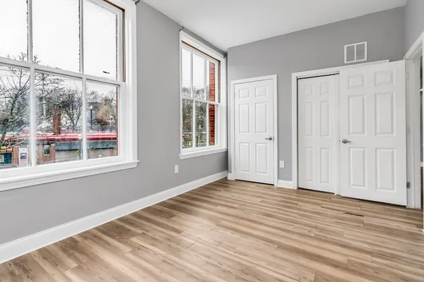 an empty room with wooden floor and windows