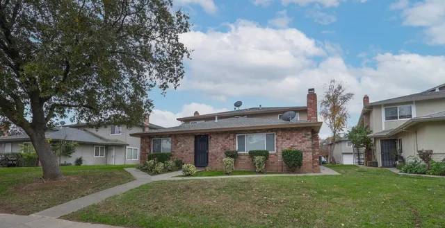 a view of a big yard in front of a brick house