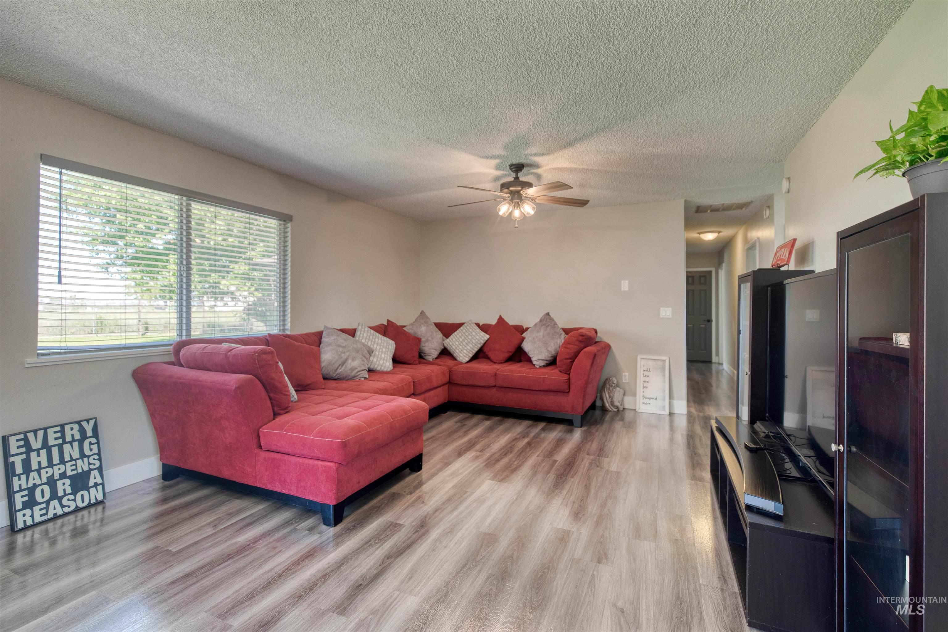 20803 Friends Road Greenleaf, ID 83626 - Photo 34 of 39 Spacious living area featuring wood-finish flooring, a large window with horizontal blinds, and neutral wall tones