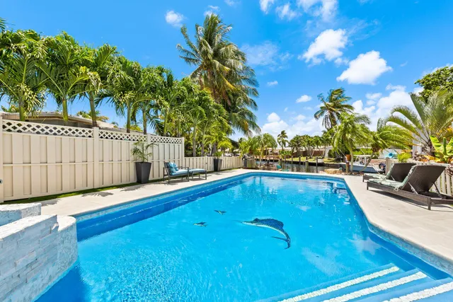 a view of a swimming pool with a lounge chair and palm trees