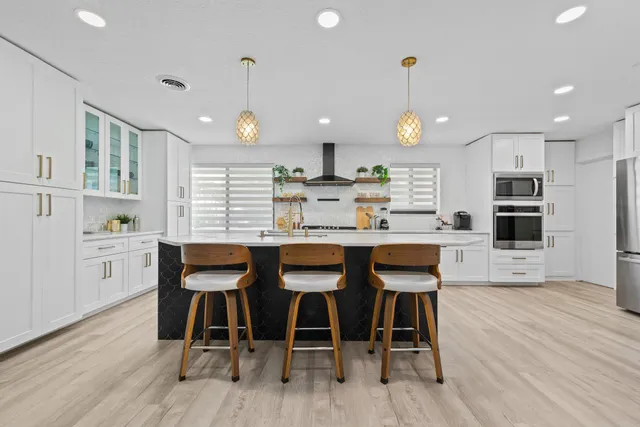 a kitchen with stainless steel appliances granite countertop wooden floor dining table and chairs