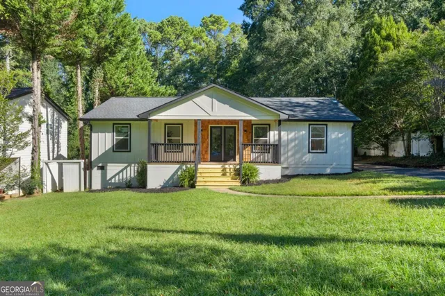 a front view of a house with a yard porch and wooden fence