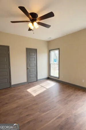 a view of an empty room with a window and wooden floor