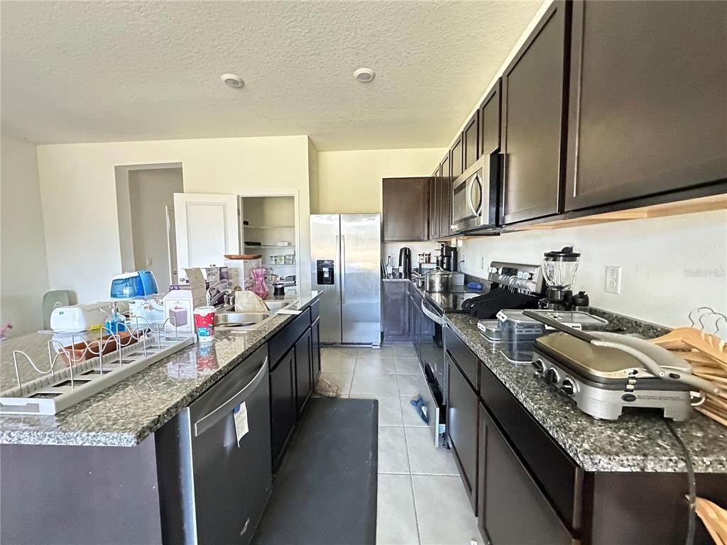 16641 Grotto Steam Place Wimauma, FL 33598 - Photo 5 of 17 a kitchen with granite countertop lots of counter top space a sink stainless steel appliances and cabinets