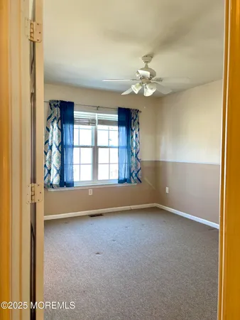 an empty room with windows and fan