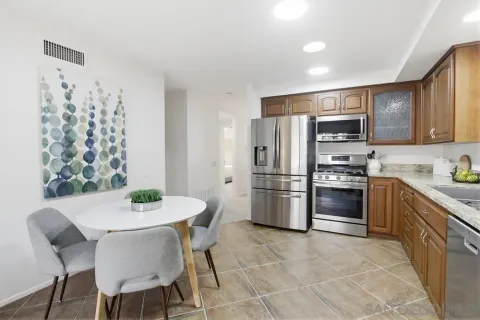 a kitchen with stainless steel appliances a refrigerator a stove a sink dishwasher a dining table and chairs with wooden floor