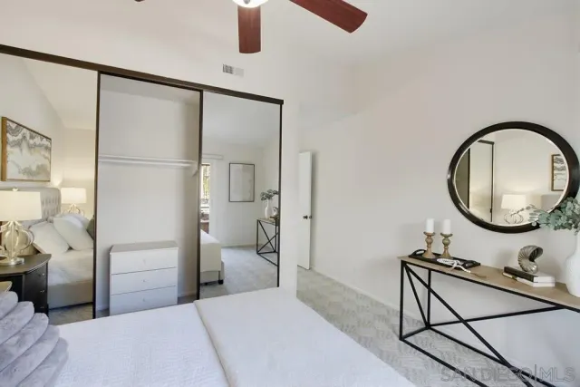 a spacious bedroom with a bed a mirror and lamp