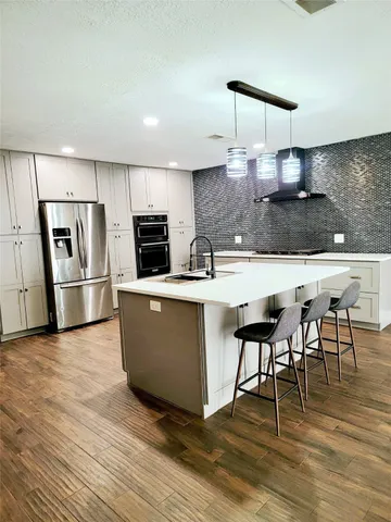 a kitchen with stainless steel appliances granite countertop a table chairs sink and cabinets