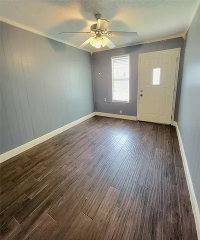 an empty room with wooden floor chandelier fan and windows