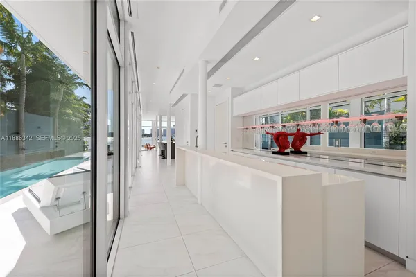 a living room with furniture a floor to ceiling window and kitchen view