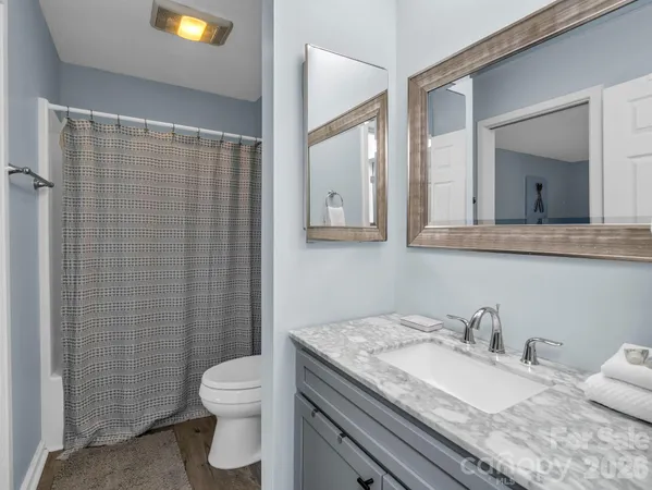 a bathroom with a granite countertop sink a toilet and a mirror
