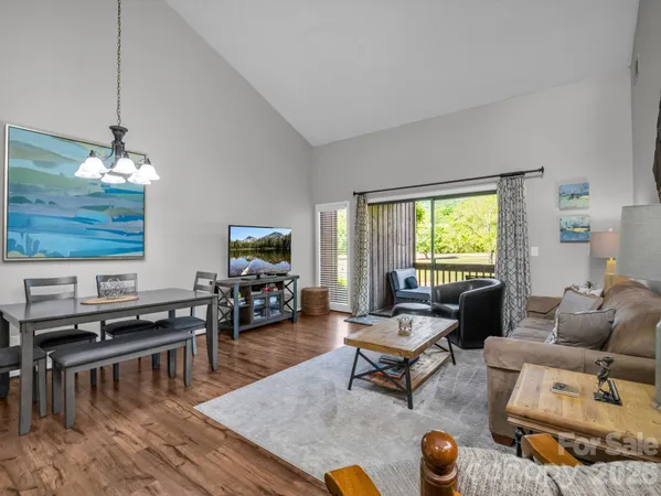 a living room with furniture and a flat screen tv with kitchen view
