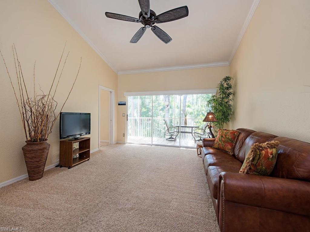 1095 Partridge Circle, Unit 201 Naples, FL 34104 - Photo 3 of 12 a living room with furniture a flat screen tv and a fireplace