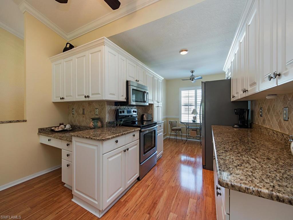 1095 Partridge Circle, Unit 201 Naples, FL 34104 - Photo 5 of 12 a kitchen with stainless steel appliances granite countertop a stove sink and refrigerator