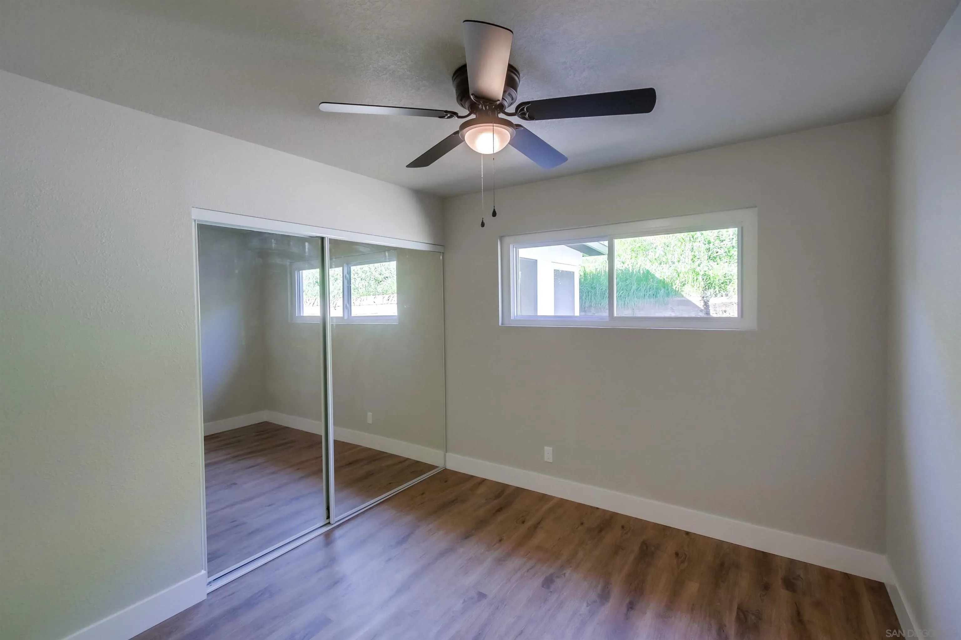 238 69th Street San Diego, CA 92114 - Photo 19 of 27 a view of an empty room with wooden floor and a window
