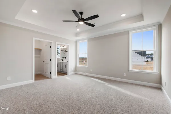 a view of a livingroom with a ceiling fan & windows