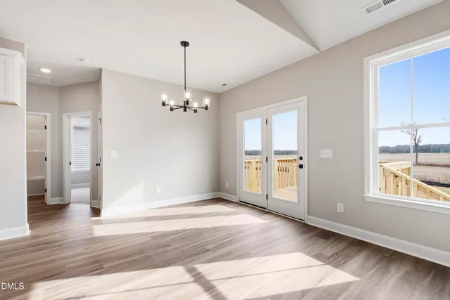 a view of an empty room with window and wooden floor
