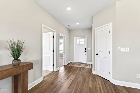 a view of a hallway with wooden floor and a bathroom