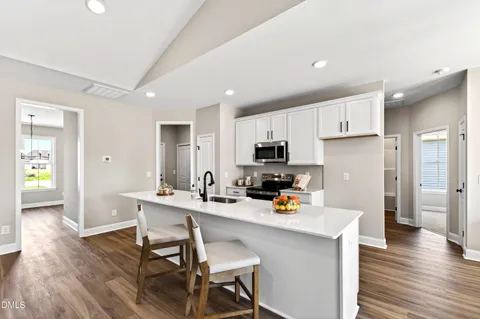 a kitchen with stainless steel appliances kitchen island granite countertop a table chairs refrigerator and sink