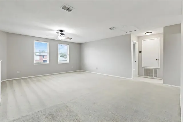an empty room with windows and chandelier fan