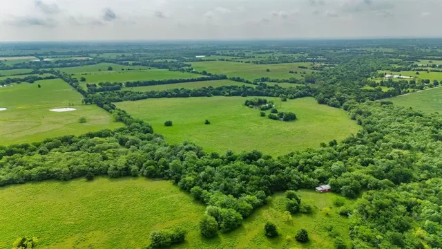 an aerial view of a houses with outdoor space and trees all around